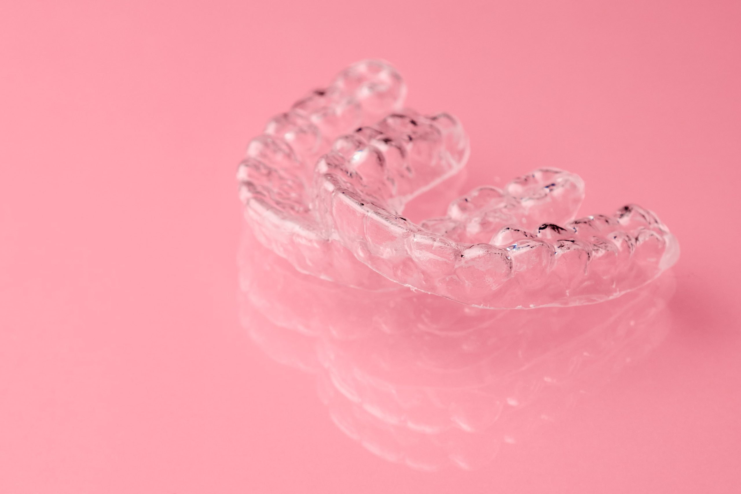 two removable braces sitting on pink background