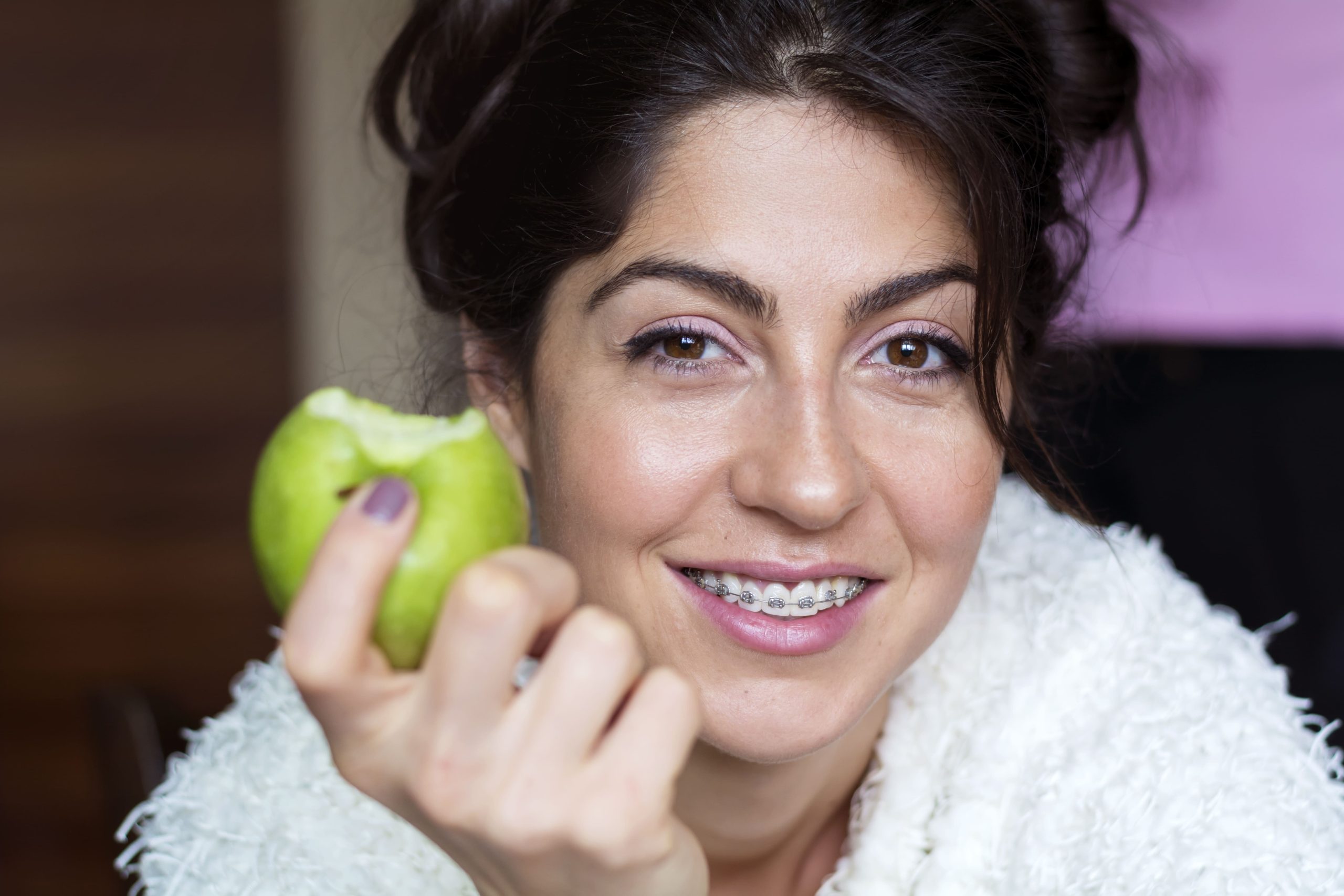 cheerful-woman-with-braces-eating-apple (1) Straighten Your Teeth After 30 - tips